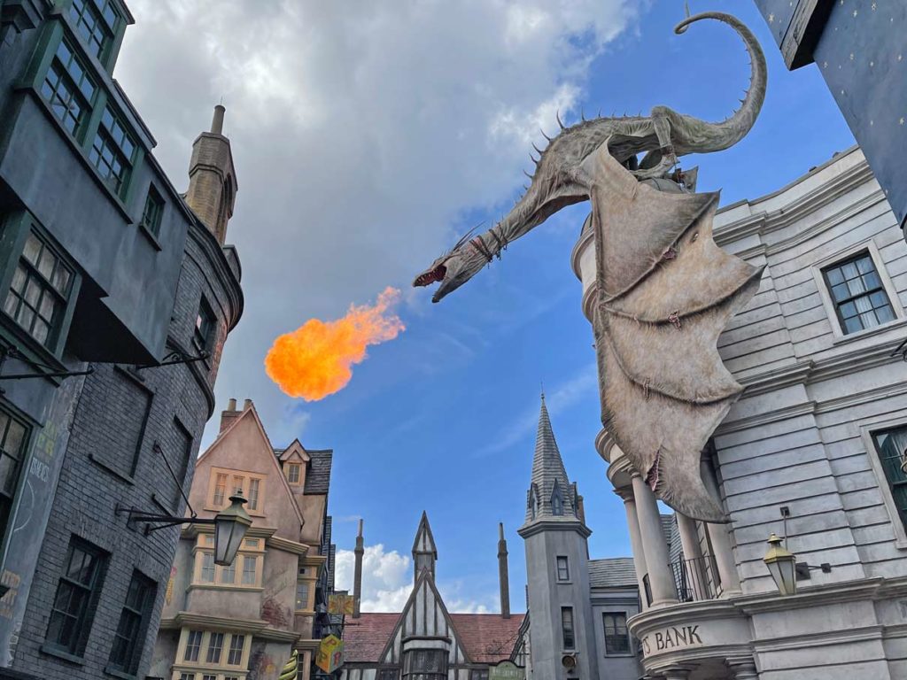 feuerspeiender-drache-sitzt-auf-gebaeude-achterbahnen-highlights-universal-studio-resort-florida-mit-kindern-freizeitpark