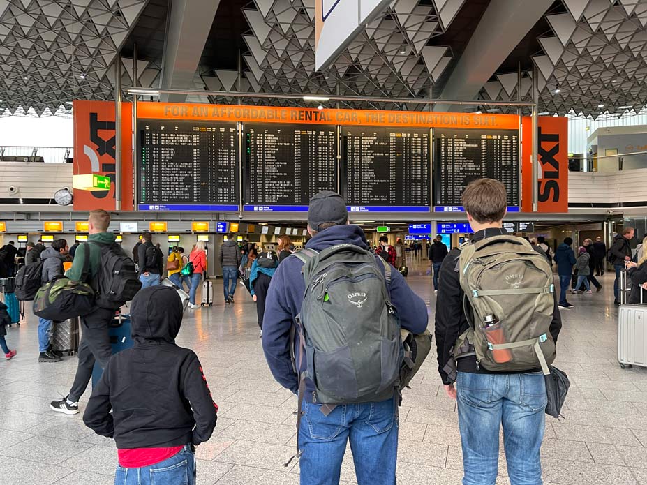 familie-steht-mit-handgepaeck-an-anzeigetafel-am-flughafen-frankfurt