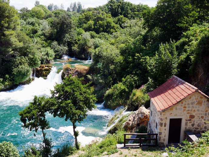 Kroatien Route - der ultimative Kroatien Familienurlaub haus-neben-wasserfall-im-krka-nationalpark-in-gruener-landschaft