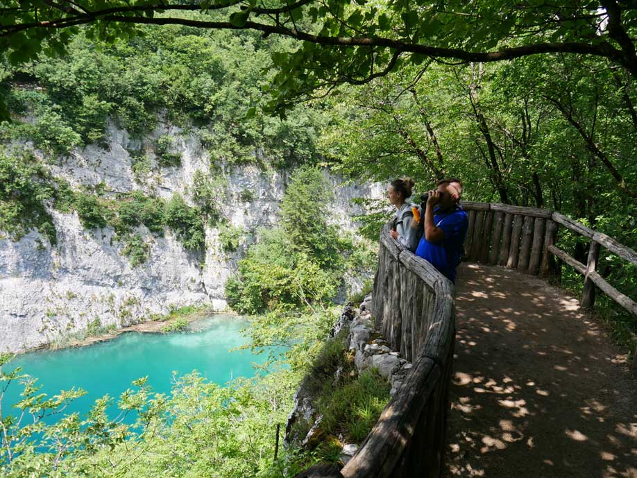 paar steht an aussichtspunkt an den plitvicer seen und blickt auf karstwände und türkises wasser