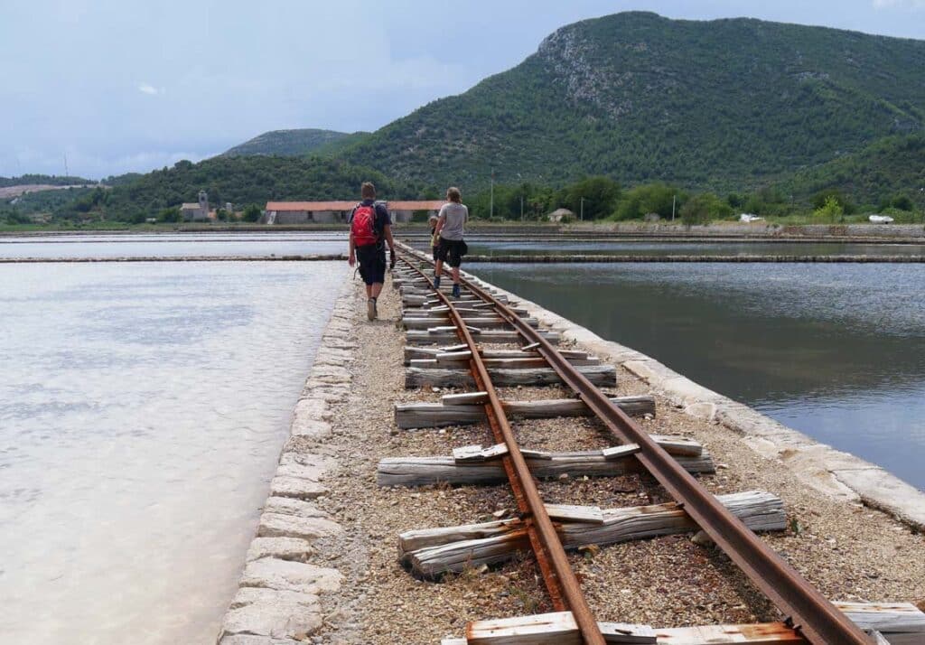 vater und sohn laufen auf alten schienen neben saline in kroatien