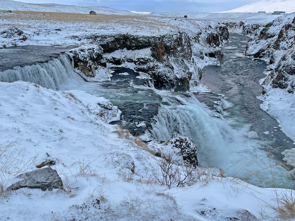16 Nordisland Sehenswürdigkeiten, die ihr nicht verpassen dürft! wasserfall-in-verschneiter-landschaft-auf-island-reykiafoss