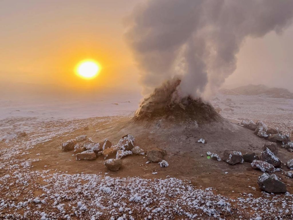 16 Nordisland Sehenswürdigkeiten, die ihr nicht verpassen dürft! rauchender-steinhaufen-sulforic-smoker-auf-nordisland-in-neblegiger-landschaft-mit-tiefstehender-sonne