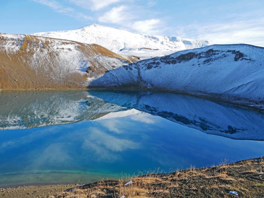 16 Nordisland Sehenswürdigkeiten, die ihr nicht verpassen dürft! blauer-vulkankratersee-im-hintergrund-verschneite-berge-viti-see