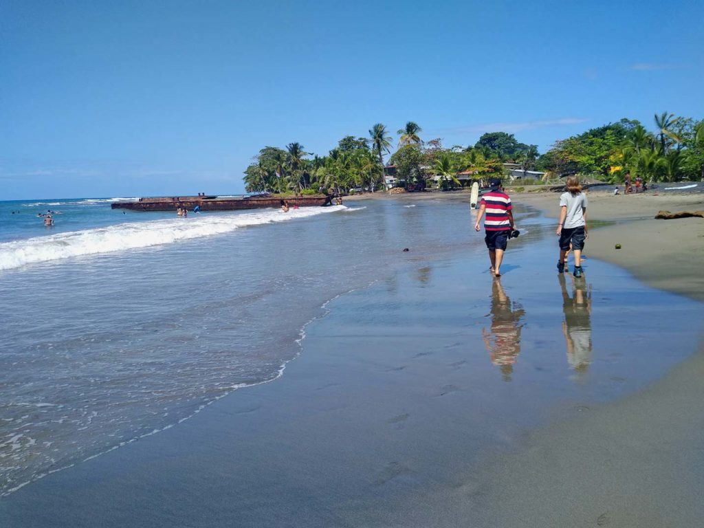 familie-spaziert-ueber-den-strand-im-meer-liegt-schiffswrack-in-puerto-viejo-an-der-karibikkueste-costa-rica