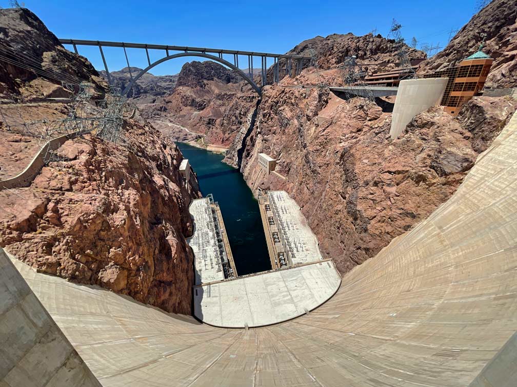Las Vegas Ausflüge - 4 Highlights in der Umgebung blick-vom-hoover-dam-auf-aufgestautes-wasser-zwischen-roten-felsen-im-hintergrund-eine-bruecke