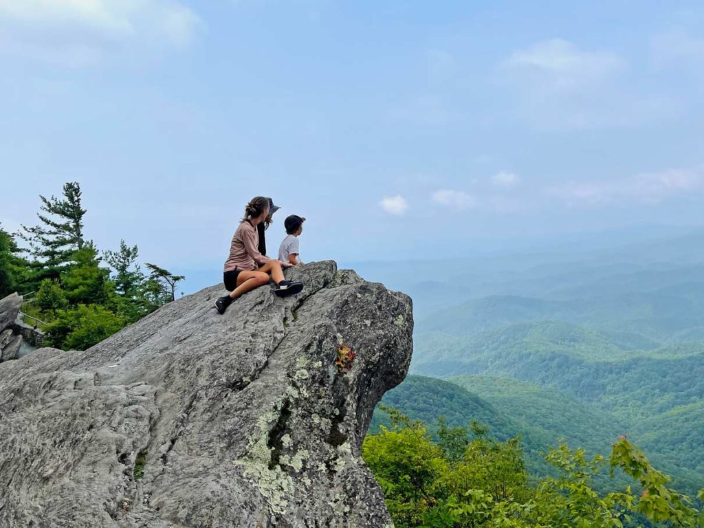 familie-sitzt-auf-grossem-stein-blowing-rock-mit-blick-auf-blue-ridge-mountains