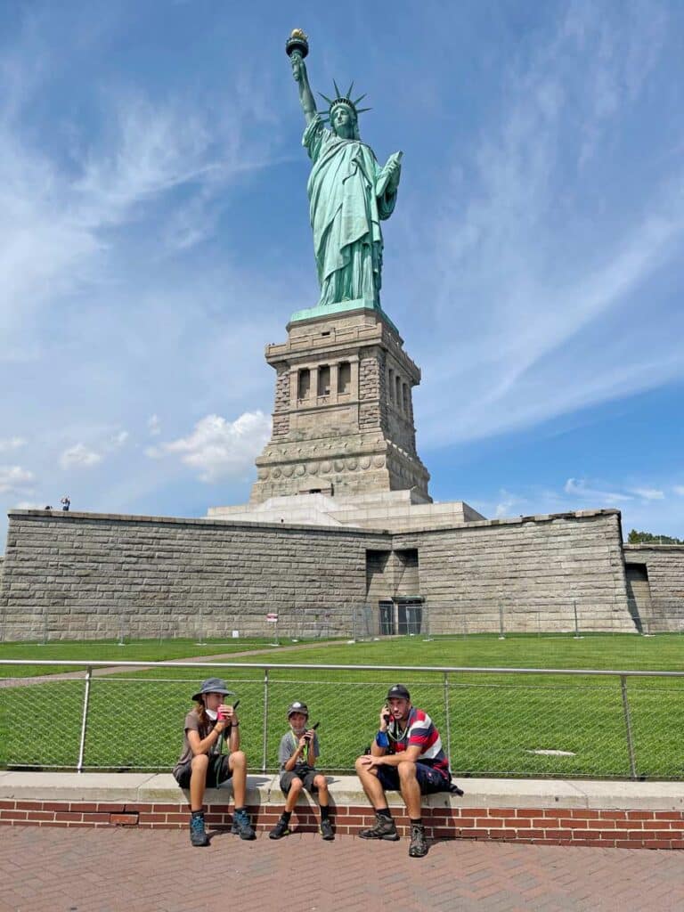 familie-sitzt-mit-audioguides-vor-freiheitsstatue-in-nyc