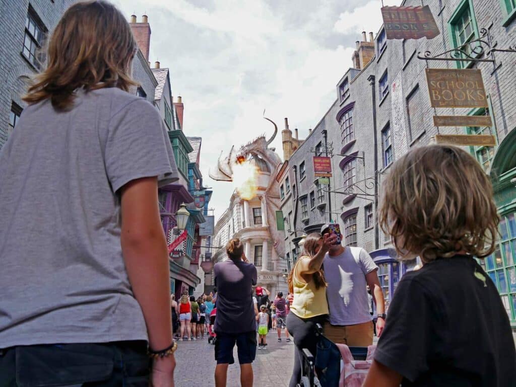 zwei-kinder-stehen-im-universal-resort-orlando-in-der-harry-potter-welt-ein-feuerspeiender-drache-sitzt-auf-der-gringotts-bank