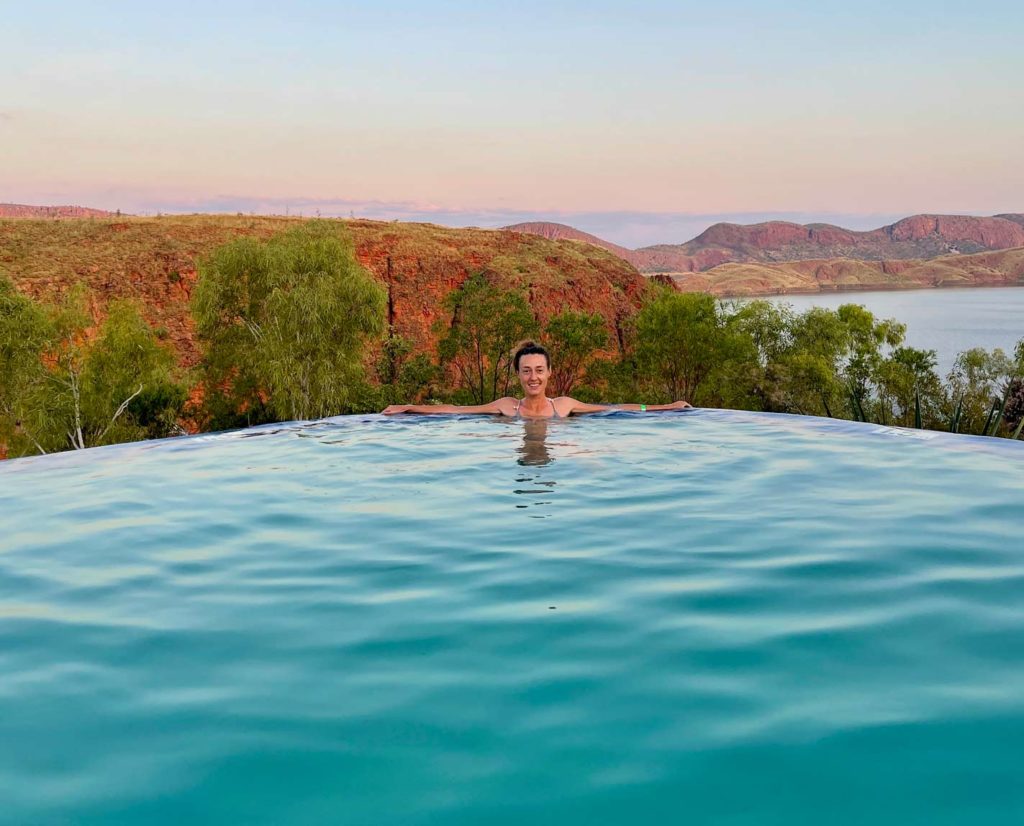 Ultimativer Guide für den Westaustralien Roadtrip frau-liegt-im-hellblauen-wasser-eines-pools-beim-sonnenuntergang-mit-blick-auf-die-landschaft-am-lake-argyle