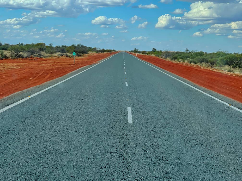 Ultimativer Guide für den Westaustralien Roadtrip schnurrgerade-strasse-westaustralien-mit-roter-erde-an-den-seiten-und-gruenen-bueschen