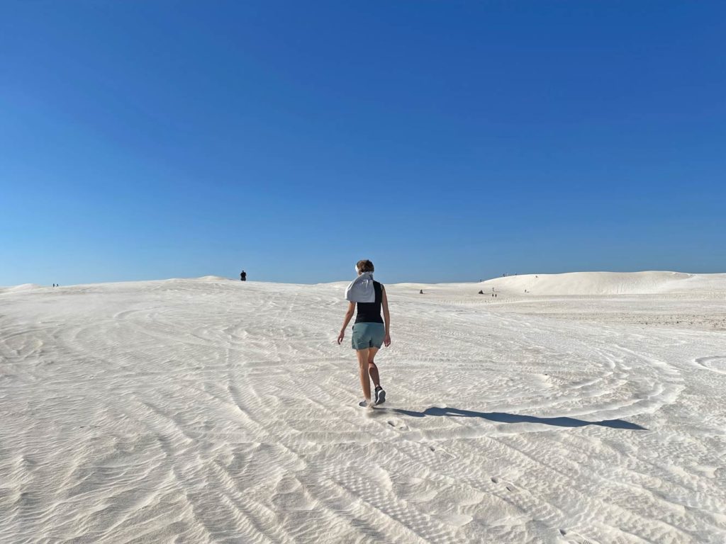 frau-laeuft-in-sommerbekleidung-mit-wehendem-kopftuch-ueber-die-weissen-sandduenen-der-lancelin-sand-dunes-an-der-westkueste-australiens