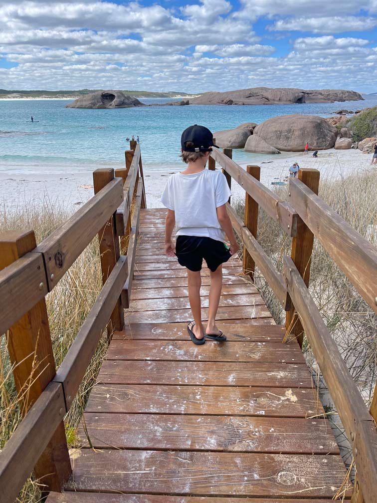SĂĽdwesten Australiens - Highlights fĂĽr die 2-Wochen Rundreise ab Perth kind-laeuft-ueber-holztreppe-auf-weissen-sandstrand-mit-felsformationen-im-wasser