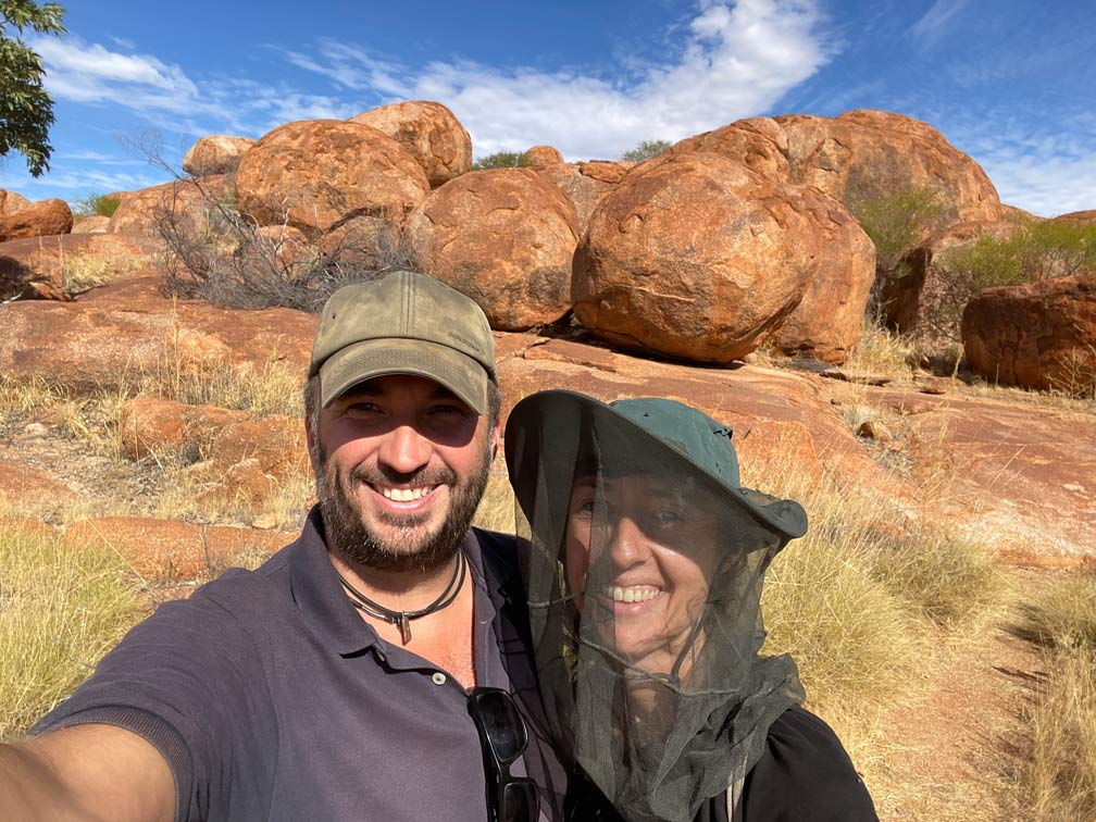 Roadtrip Northern Territory - Rundreise von Darwin zum Uluru ehepaar-lacht-in-kamera-frau-traegt-moskitohut-im-hintergrund-rote-runde-felsen-in-nordaustralien