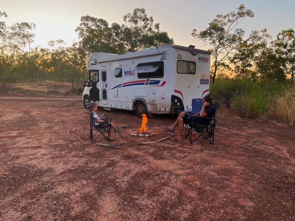 Roadtrip Northern Territory - Rundreise von Darwin zum Uluru vater-und-sohn-am-lagerfeuer-im-outback-sitzen-vor-wohnmobil-auf-campingstuehlen