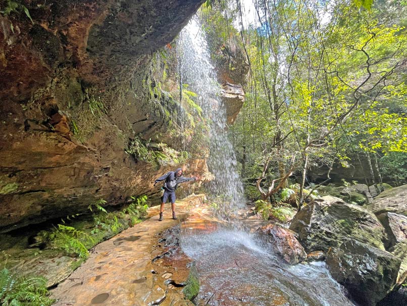 Blue Mountains in Australien - Naturparadies vor den Toren Sydneys mann-laueft-hinter-wasserfall-am-grand-canyon-track-in-den-blue-mountains-entlang
