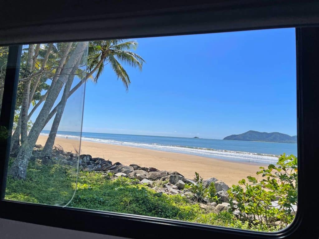 Blick-aus-Wohnmobilfenster-auf-Palmenstrand-Australien
