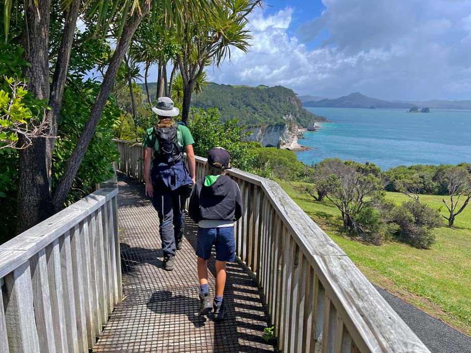 kinder-laufen-auf-boardwalk-mit-blick-auf-das-meer-am-cathedral-cove-walk-neuseeland