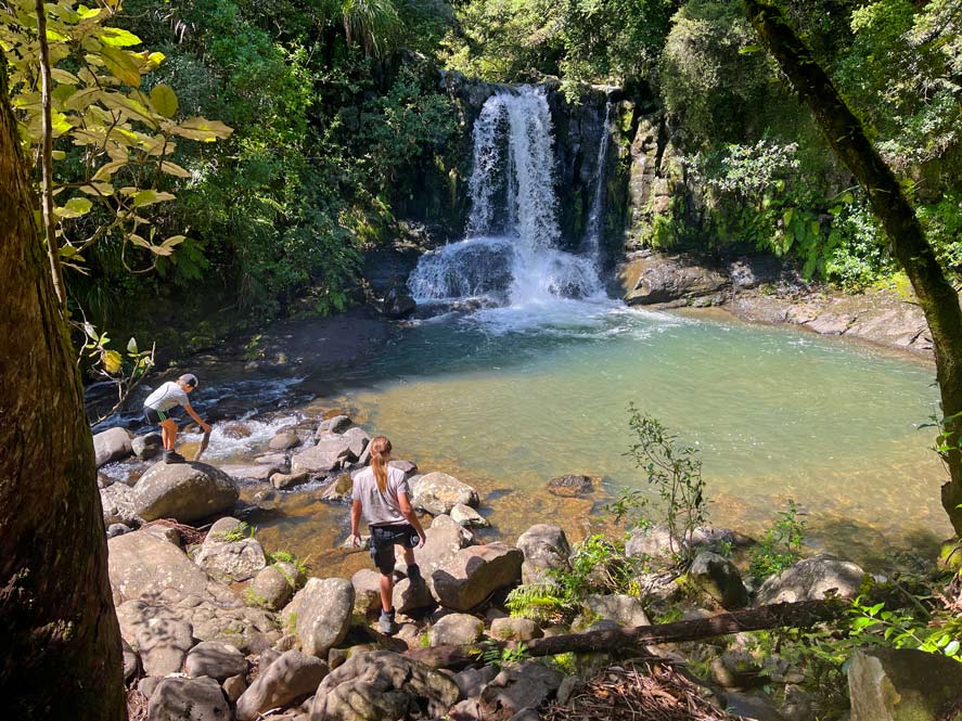 waiau-falls-tropischer-wasserfall-kinder-klettern-davor-auf-steinen-neuseeland-routenplanung