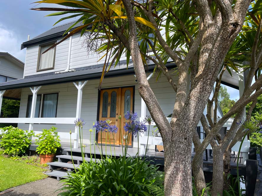 weisses-ferienhaus-mit-veranda-und-palme-davor-in-new-plymouth-neuseeland