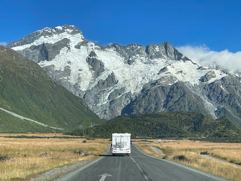 wohnmobil-auf-der-strasse-faehrt-auf-grosse-bergkette-mount-cook-mit-schnee-bedeckt-zu-in-neuseeland-auf-der-suedinsel