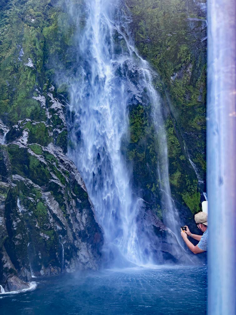 mann-fotografiert-stirling-fall-wasserfall-aus-dem-boot-heraus-auf-dem-milford-sound