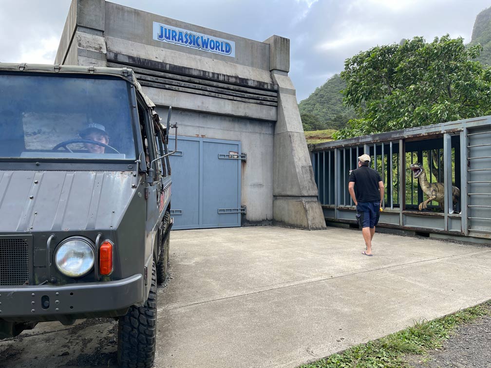 drehort-jurassic-world-mann-laeuft-auf-bunker-zu-rechts-dino-kaefig-links-jeep