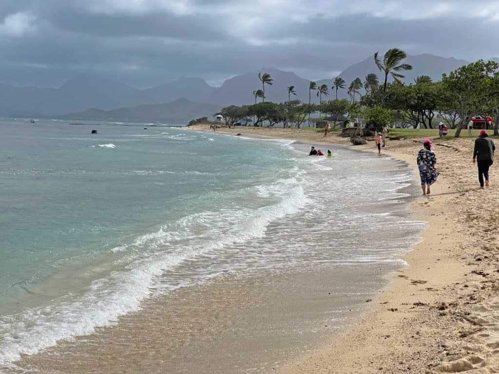 sandstrand-auf-oahu-mit-palmen-und-bewoelktem-himmel