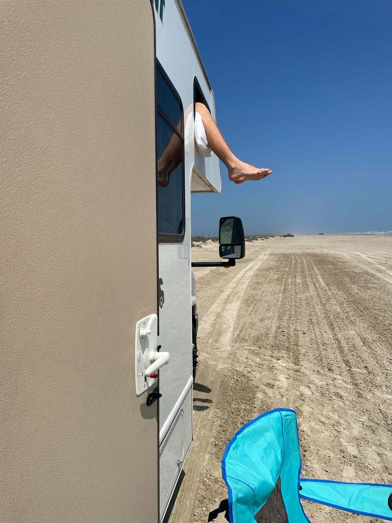 Campingplätze USA | Der ultimative Guide zur Stellplatzsuche fuesse-baumeln-aus-wohnmobil-fenster-am-strand-wohnmobil-roadtrip-usa-campingplaetze-texas