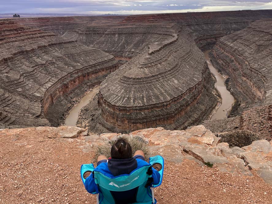 Campingplätze USA | Der ultimative Guide zur Stellplatzsuche mann-sitzt-auf-campingstuhl-vor-einem-canyon-campingplatz-usa-state-park-goosenecks-state-park