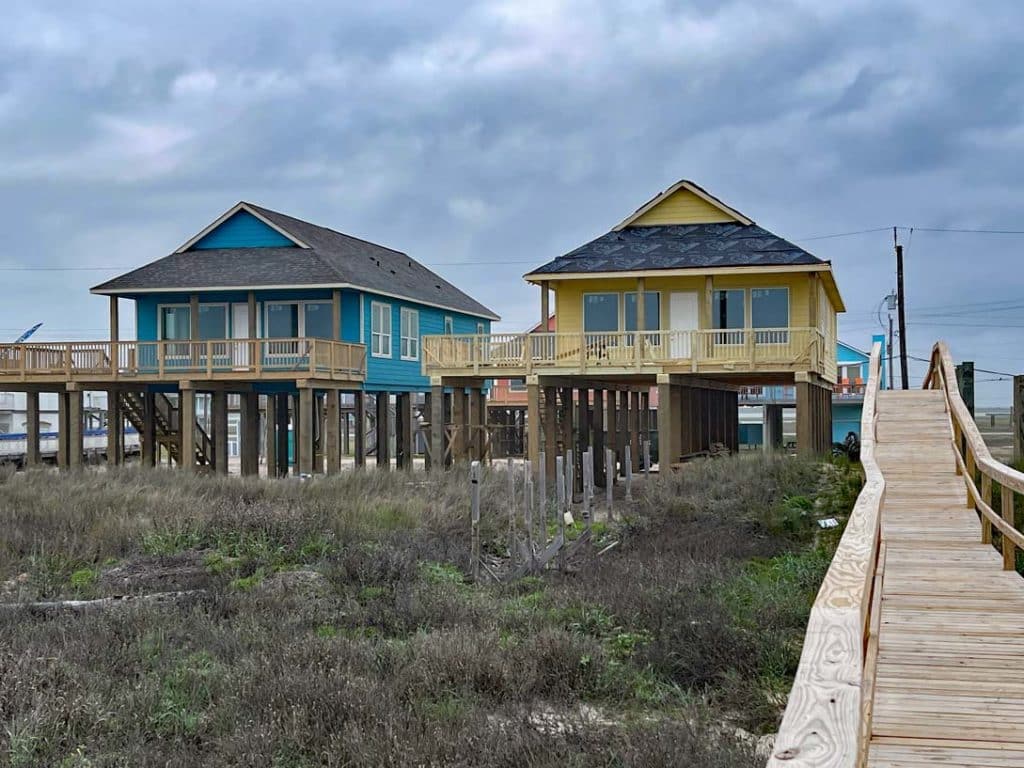 bunte-holzhaeuser-auf-stegen-am-strand-hinter-duenen-in-texas