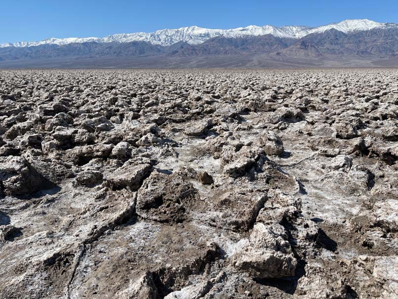 devils-golf-course-death-valley-aufgesprungene-salzkrusten-im-hintergrund-schneebedeckte-berge