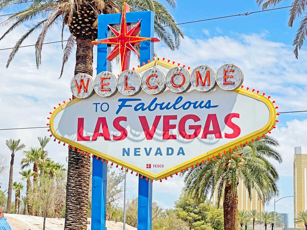 bekannter-fotospot-in-las-vegas-das-weisse-schild-mit-gelben-rahmen-und-dem-schriftzug-welcome-to-fabulous-las-vegas-mit-palmen-im-hintergrund