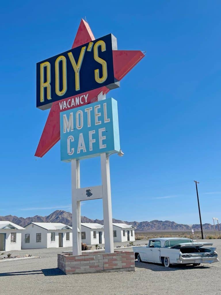 grosses-schild-roys-motel-route-66-roadtrip-usa-mit-blauem-cadillac-davor