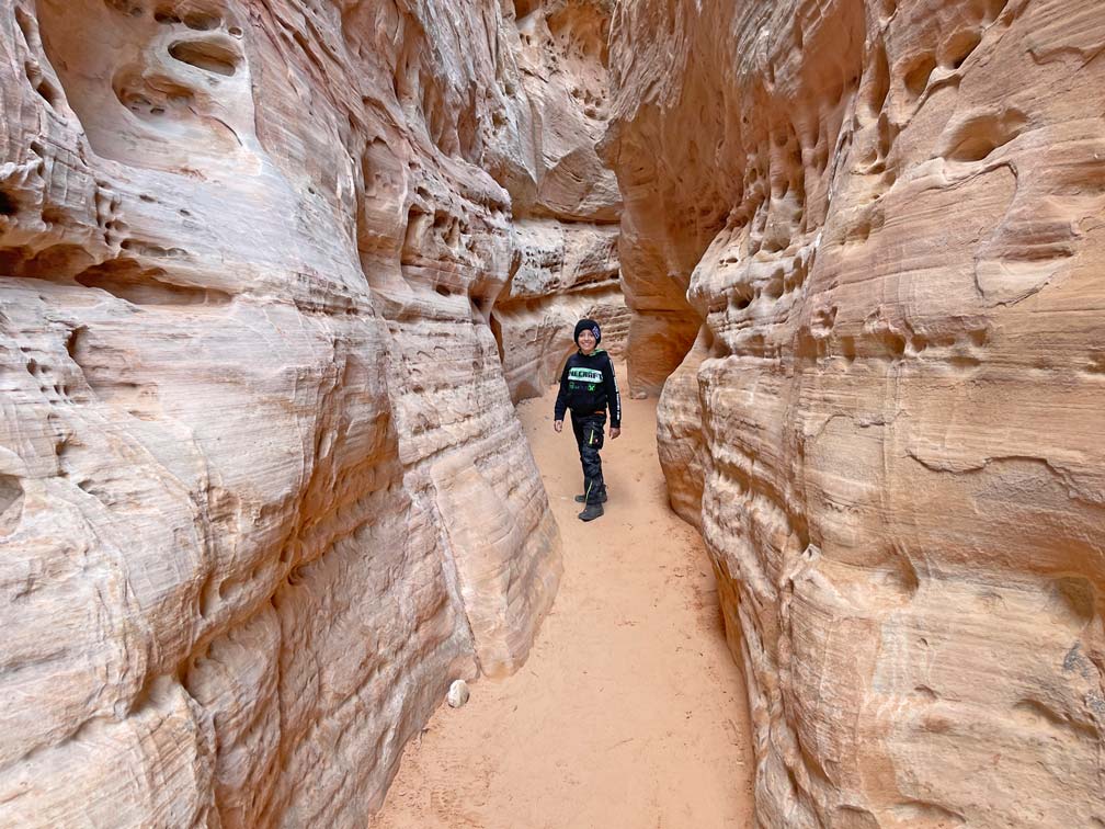 kind-wandert-durch-roten-slot-canyon-mit-rotem-sand-auf-dem-boden-im-valley-of-fire-state-park