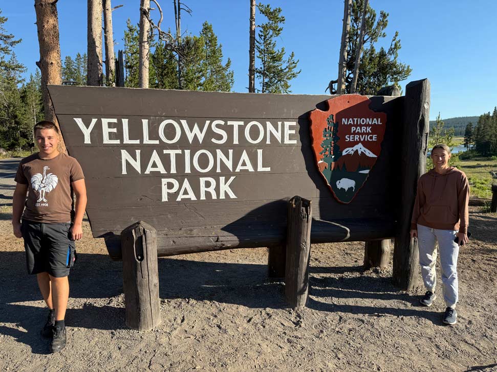 mutter-und-sohn-vor-yellowstone-nationalpark-eingagnsschild