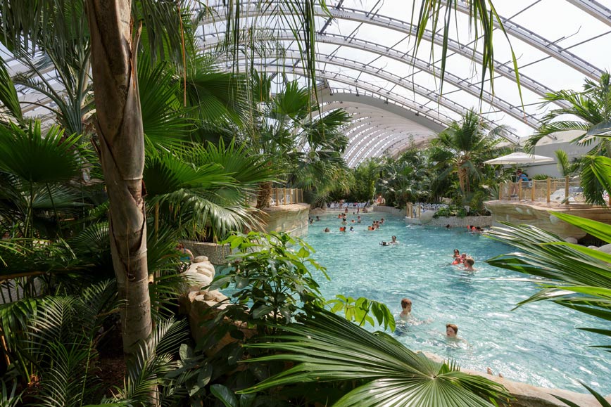 Center Parcs Les Trois Forets - Familienurlaub im Elsass urlauber-im-ueberdachten-pool-mit-tropischen-palmen-an-der-seite