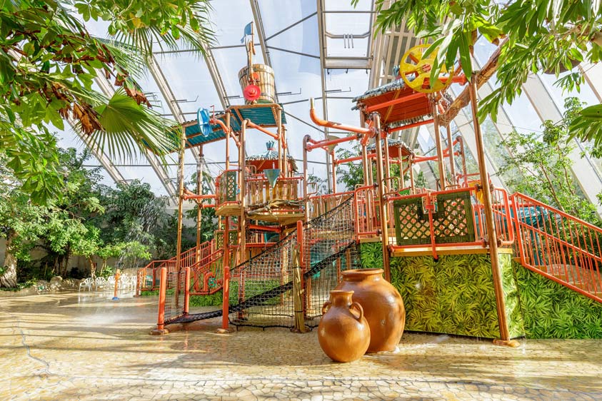 bunter-wasserspielplatz-in-ueberdachtem-schiwmmbad-in-tropischer-umgebung