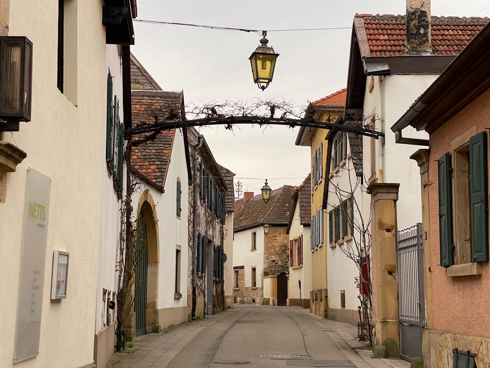 mittelalterliche-altstadt-gimmeldingen-zu-beiden-seiten-der-gasse-haeuserreihen-gelbe-laternenlampen-ueber-dem-weg