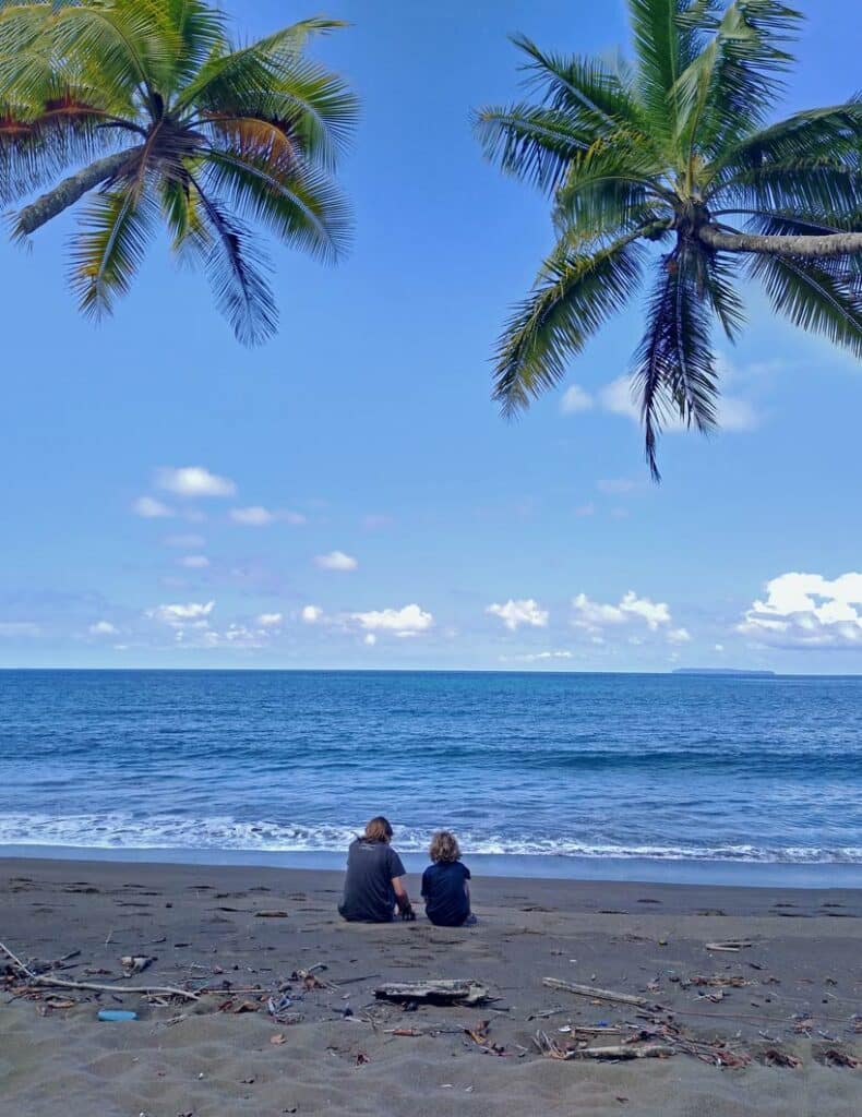 Costa Rica Rundreise - Diese 9 Etappen dürft ihr nicht verpassen! zwei-kinder-sitzen-am-sandstrand-in-costa-rica-unter-palmen