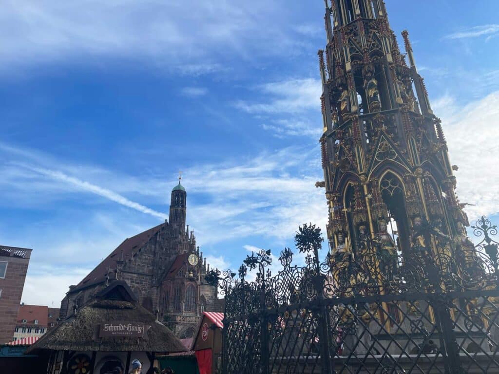 Nürnberg Sehenswürdigkeiten - Städtetrip oder Zeitreise? rechts-schoener-brunnen-mit-aufwendigen-bunten-figuren-links-frauenkirche