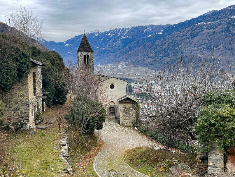 Bernina Express vs. Regionalbahn: Tipps für die perfekte Zugreise durch die Schweizer Alpen kirche-santa-perpetua-in-tirano-berge-im-hintergrund