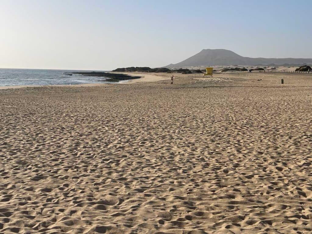 Unsere Top 11 Strände auf Fuerteventura weitlaeufiger-sandstrand-an-duenen-von-corralejo-mit-gelbem-badehaus