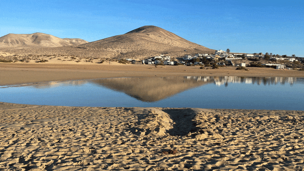 sandstrand-mit-lagune-in-der-sich-berg-spiegelt