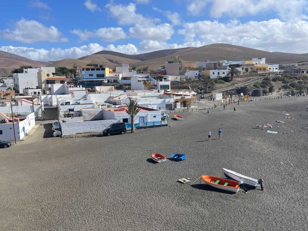 Unsere Top 11 Strände auf Fuerteventura schwarzer-sandstrand-auf-fuerteventura-mit-weissen-haeusern-und-bunten-booten-am-strand