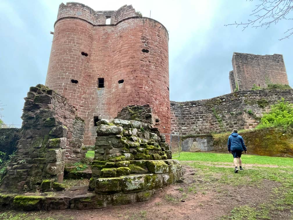 Wandern im Dahner Felsenland 🥾 7+ Tipps mann läuft auf burgruine neudahn zu rote sandsteinburg