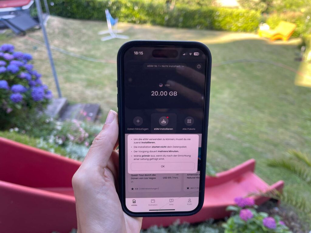 Die beste eSIM für den USA Urlaub handy wird in der hand gehalten und auf dem bildschirm stehen erklärung, wie eine esim in den usa funktioniert