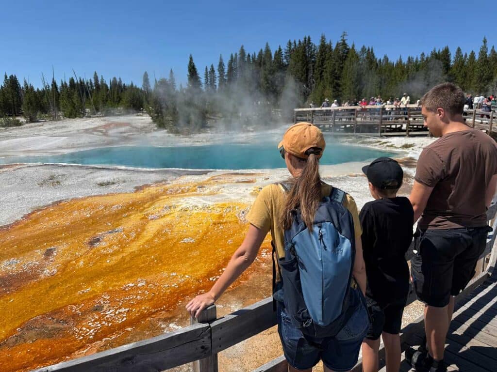 familie steht an buntem geothermalen becken im yellowstone nationalpark