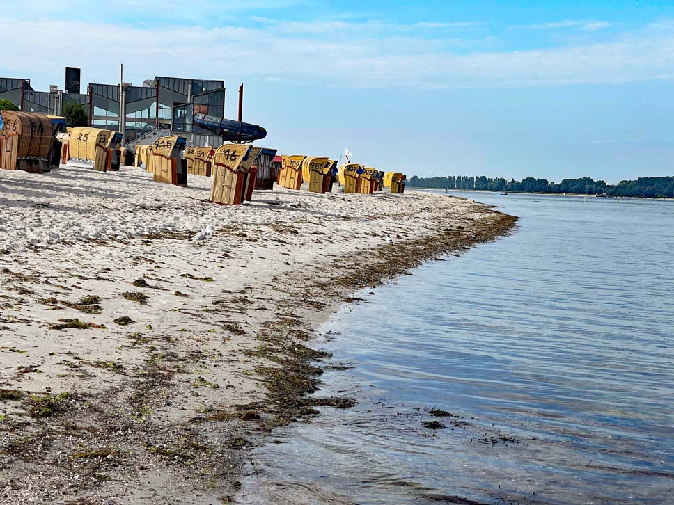 strand in laboe mit strandkörben, dahinter lost place altes schwimmbad