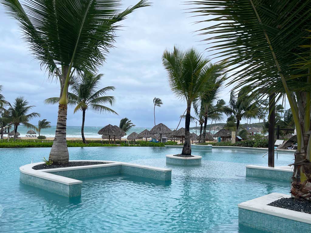 pool mit palmen direkt mit blick auf strand in der dominikanischen republik